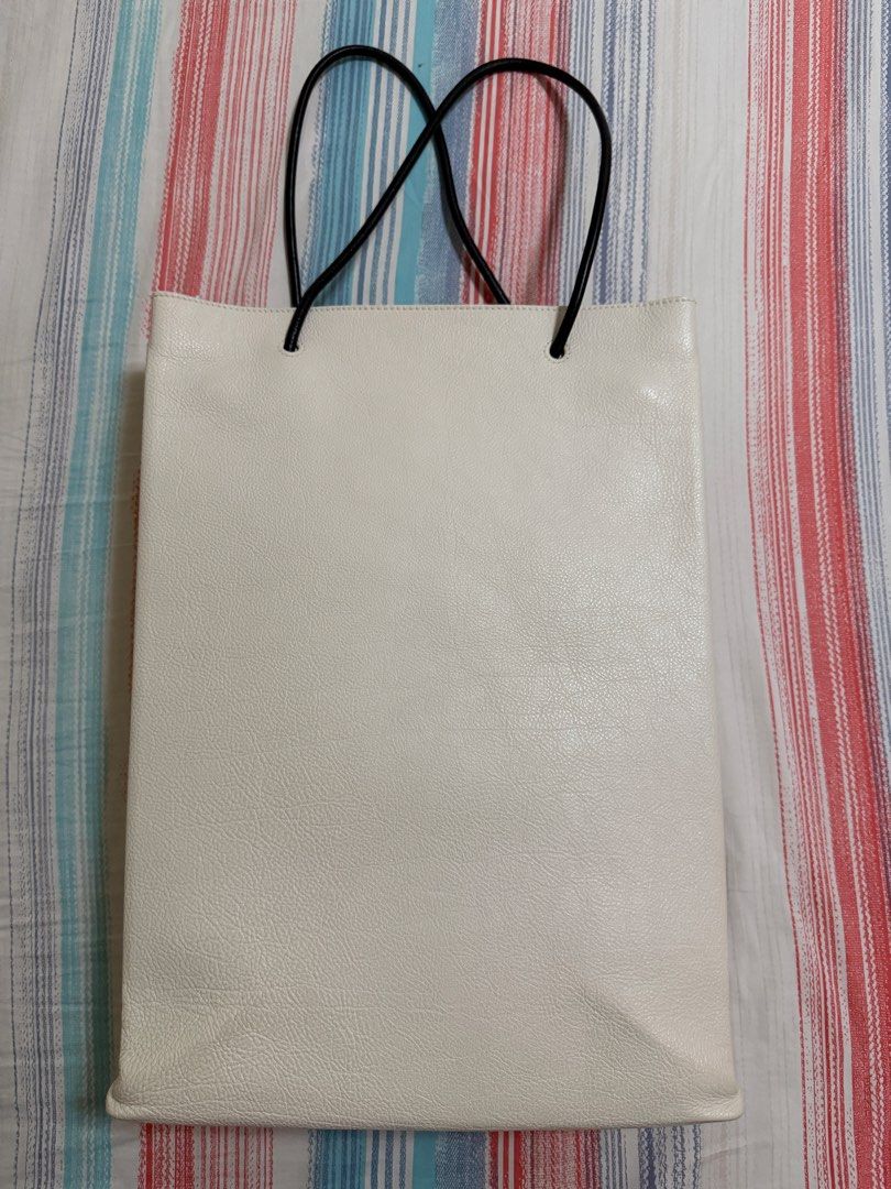 AUTHENTIC Balenciaga Shopping Bag (Category: Luxury Bags & Wallets) located in Quezon City. Submitted by declutter1ngmama (Listing ID 1429903636, Image 2). Description: White tote bag from Balenciaga. Main bag in White Calf Leather with black handles and the brand name printed on the front. Includes a dust bag. Bought in Balenciaga Greenbelt 5 for 80k+ Medium size 32 x 44 x 11 centimeters (12 x 17 x 4 inches.