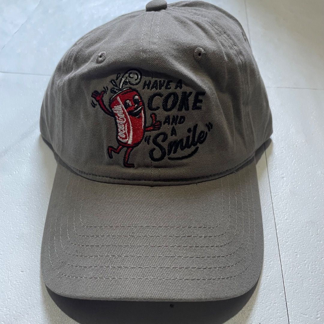Coca-Cola Have a Coke and a Smile Cap (Category: Caps & Hats) located in Caloocan City. Submitted by wildgem_dacf04 (Listing ID 1429908496, Image 1). Description: Cap features the iconic Coca-Cola logo with the phrase "Have a Coke and a Smile". It has a classic baseball cap design with a curved brim and an adjustable strap at the back. The cap is a neutral color, making it versatile for everyday wear. The Coca-Cola logo is embroidered on the fron