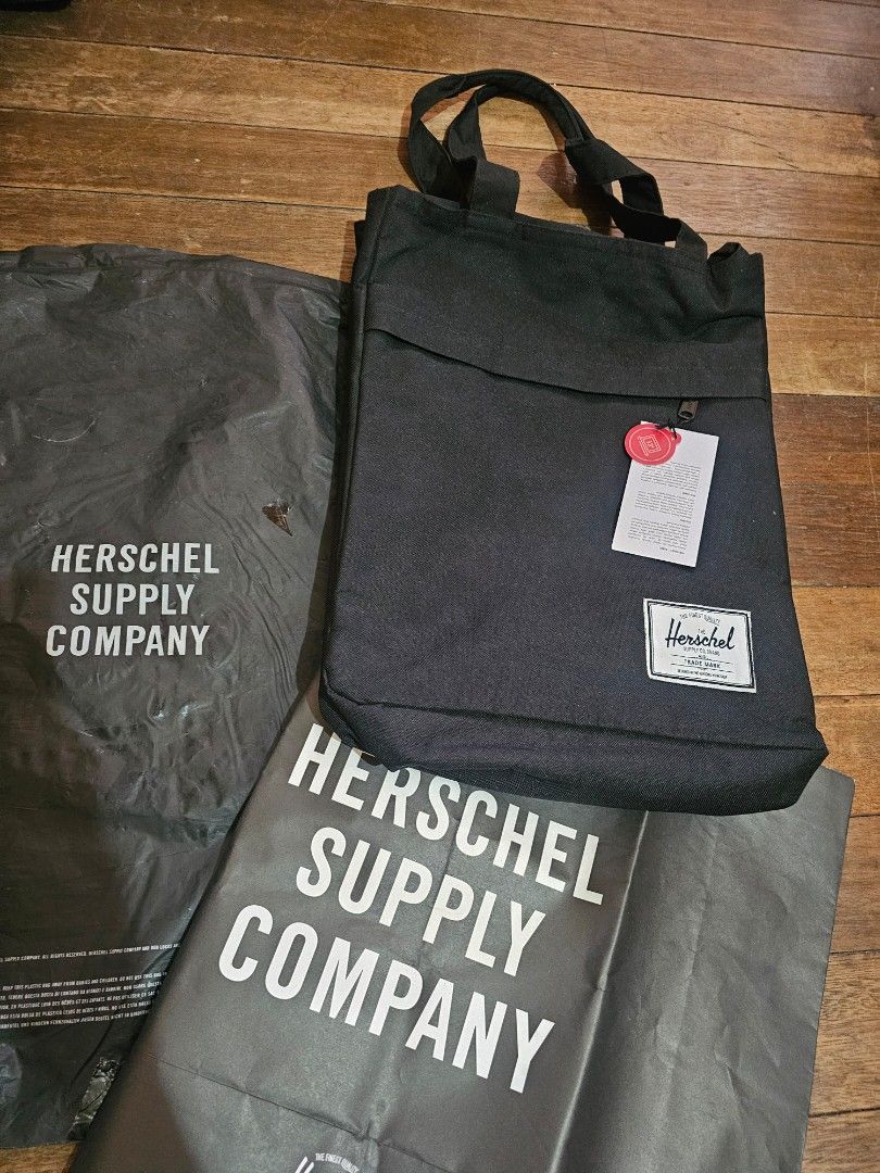 Herschel Supply Co. Tote Bag (Category: Laptop Bags & Sleeves) located in Manila. Submitted by onlinesmartshopping12 (Listing ID 1429906664, Image 1). Description: Herschel Supply Co. tote bag features a black exterior and a red and white striped interior. It has a front pocket and a zippered main compartment. The bag includes a tag indicating it can fit a 13-inch laptop. The bag has two handles for carrying..