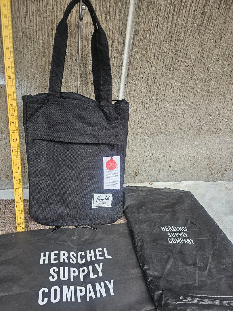 Herschel Supply Co. Tote Bag (Category: Laptop Bags & Sleeves) located in Manila. Submitted by onlinesmartshopping12 (Listing ID 1429906664, Image 2). Description: Herschel Supply Co. tote bag features a black exterior and a red and white striped interior. It has a front pocket and a zippered main compartment. The bag includes a tag indicating it can fit a 13-inch laptop. The bag has two handles for carrying..