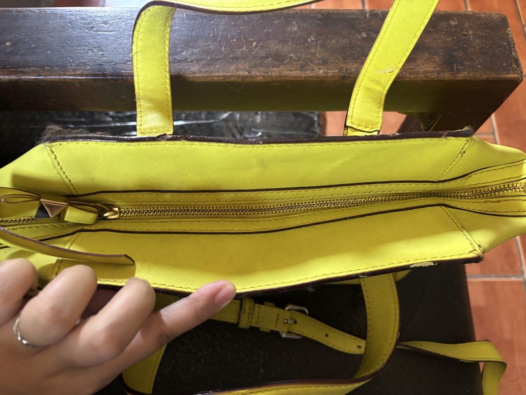 Kate Spade New York Handbag (Category: Luxury Bags & Wallets) located in Paniqui. Submitted by daily_finds (Listing ID 1429868433, Image 3). Description: Bright yellow Kate Spade handbag with a bow design on the front. Features a top zipper closure and a detachable shoulder strap. The interior lining is a light color with a polka dot pattern. Includes a Kate Spade New York tag inside. Has a top handle and a gold-tone hardware. Cons: Has scratches