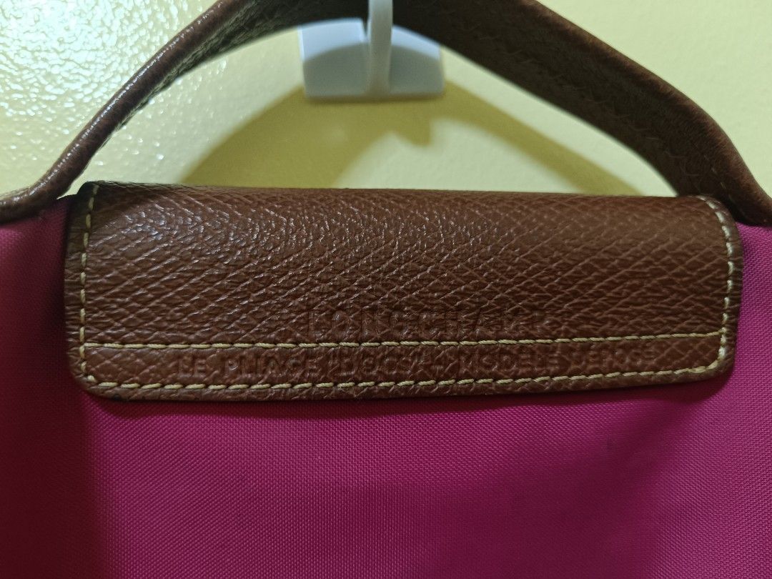 Longchamp Le Pliage Travel Bag (Category: Luxury Bags & Wallets) located in Trece Martires City. Submitted by declutterbyedi (Listing ID 1429982875, Image 3). Description: Authentic Longchamp Le Pliage travel bag in a vibrant magenta color. Features a brown leather flap with a gold-tone snap closure and handle. The bag has a zipper closure and a Longchamp logo charm. From Switzerland, needs bag cleaning..