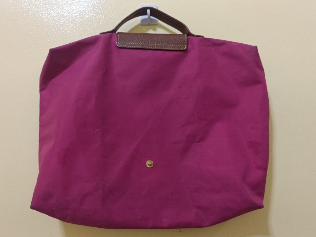 Longchamp Le Pliage Travel Bag (Category: Luxury Bags & Wallets) located in Trece Martires City. Submitted by declutterbyedi (Listing ID 1429982875, Image 2). Description: Authentic Longchamp Le Pliage travel bag in a vibrant magenta color. Features a brown leather flap with a gold-tone snap closure and handle. The bag has a zipper closure and a Longchamp logo charm. From Switzerland, needs bag cleaning..