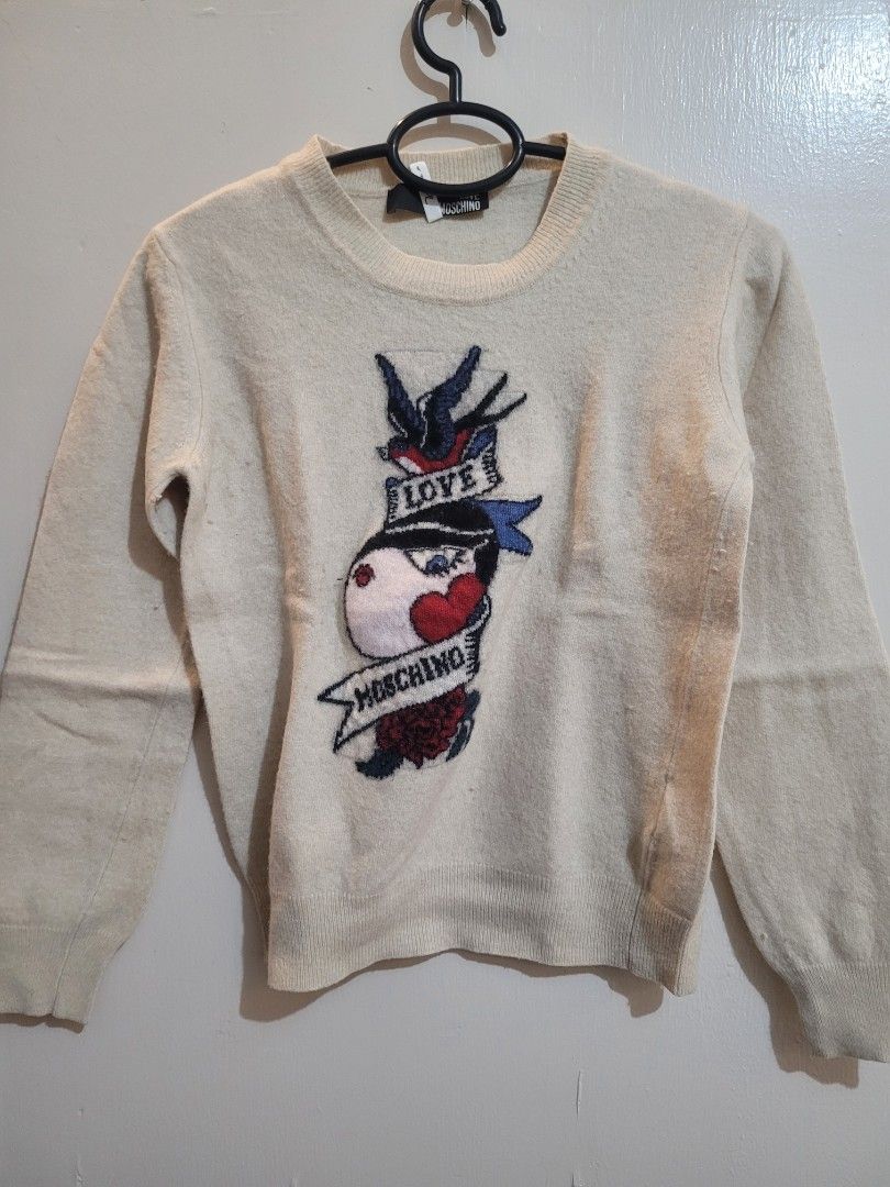 Love Moschino Sweater (Category: Coats, Jackets and Outerwear) located in Valenzuela. Submitted by flzoneeee (Listing ID 1429959285, Image 1). Description: Cream-colored sweater from Love Moschino. Features a graphic design on the front. The sweater has long sleeves and a round neckline. The brand tag is visible. A classic and stylish piece for your wardrobe..