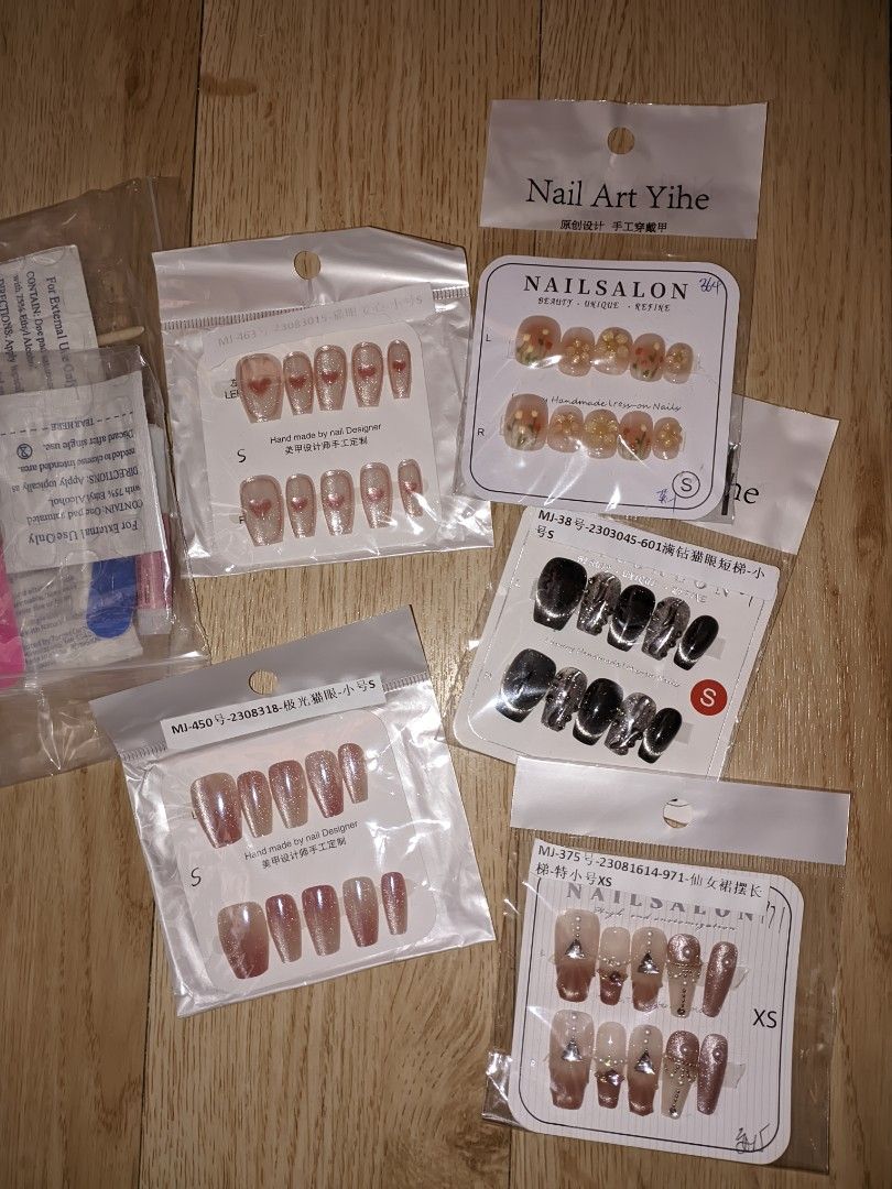 Premium Handmade Nail Art Press-on Nails Set (Category: Hands & Nails) located in Pasig City. Submitted by pottyhead.22 (Listing ID 1429990525, Image 1). Description: Set of premium press-on nails in various designs and sizes. Includes sets with heart designs, floral accents, and glitter effects. Available in sizes S and XS. Each set comes with multiple nails for a complete manicure. Designs include a mix of solid colors and patterned nails. ₱250