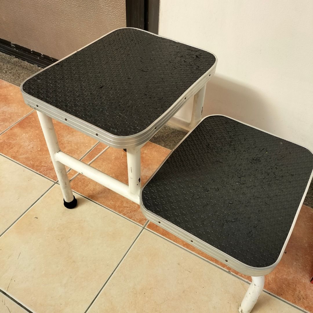 Sturdy Two-Step Stool (Category: Chairs) located in Paranaque City. Submitted by decluttering-all (Listing ID 1429929925, Image 2). Description: Two-step stool features a sturdy metal frame with non-slip surfaces on each step. The steps are rectangular and have a textured, black surface. The frame is white with some signs of wear. It's a practical item for reaching higher places in your home or workspace. Sturdy Two-Step Stool - Textured steps fo