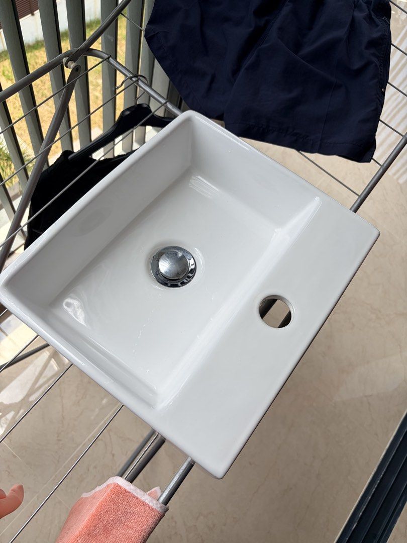 White Ceramic Sink - Rectangular (Category: Bathroom & Kitchen Fixtures) located in Singapore. Submitted by cczero (Listing ID 1429873019, Image 1). Description: 34 x 30 x 12cm Features a rectangular design with a single faucet hole and a chrome drain. Perfect for a bathroom or powder room renovation. Includes the drain assembly..