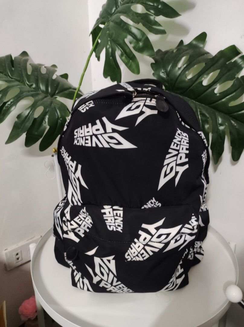 Givenchy Black and White Urban Backpack (Category: Backpacks) located in Santa Rosa. Submitted by sassycollection. (Listing ID 1435333756, Image 2). Description: Nylon canvas backpack in black featuring logo pattern printed in white throughout. Grained leather carry handle at top. Adjustable padded grosgrain shoulder straps. Zippered compartment at face. It has some crackings in zipper handle leather. Tonal leather panel and leather logo patch at