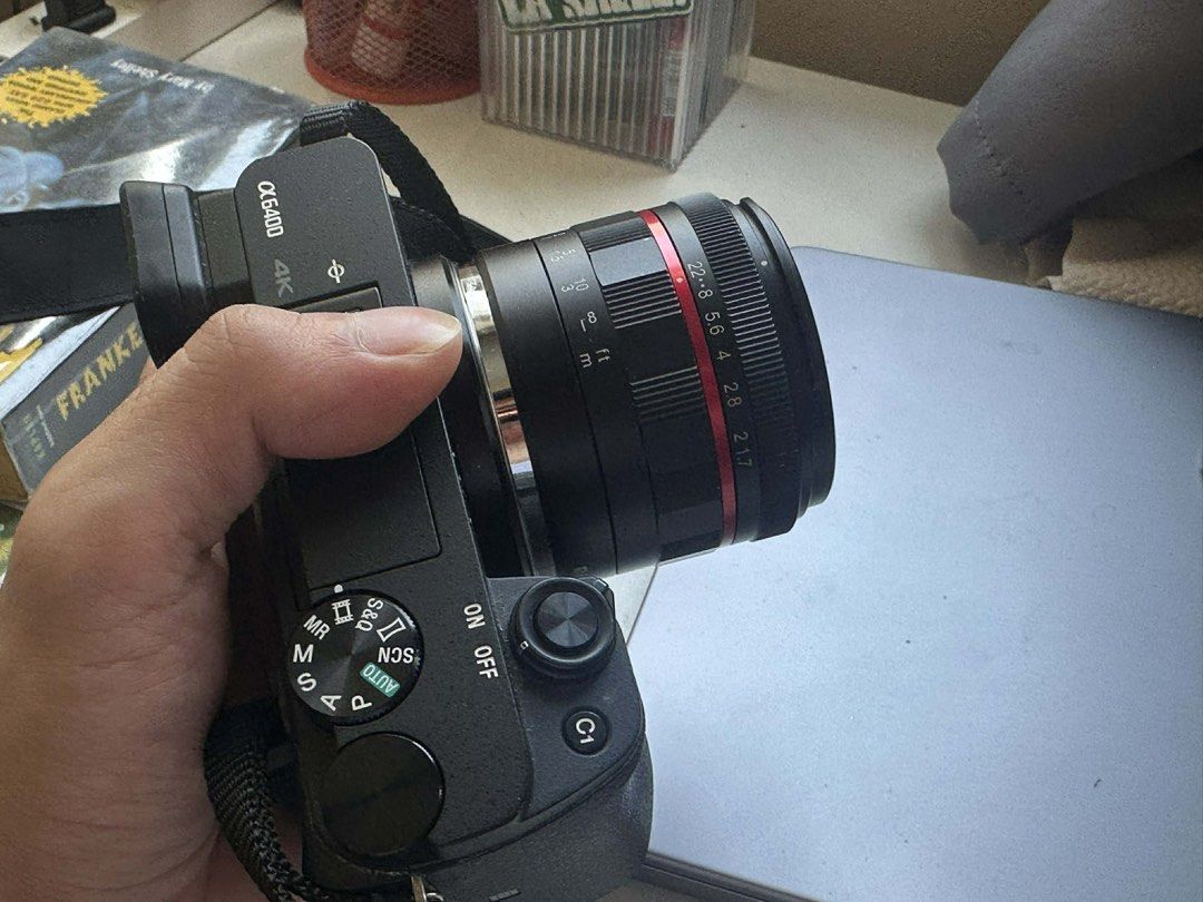 Meike 50mm Lens (Lens Only) (Category: Lens & Kits) located in Quezon City. Submitted by zadivinele78018 (Listing ID 1435199673, Image 2). Description: - Sony Alpha a6400 camera (black body) - Includes Meike 50mm lens - Lens features a red ring and 1.7 aperture - Comes with camera strap - Features various dials and buttons.