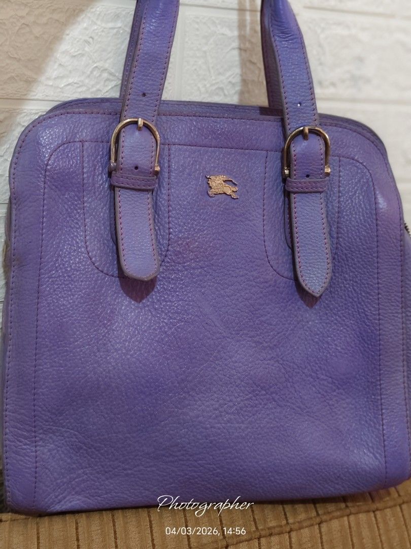 Burberry Purple Leather Handbag (Category: Luxury Bags & Wallets) located in Bulacan. Submitted by dstore4u (Listing ID 1430042203, Image 1). Description: Purple leather handbag with gold-tone hardware. Features a top handle design with buckle details. The interior has a check pattern lining. Includes a zipper closure with a Burberry branded zipper pull. The bag has a textured leather exterior and a small logo on the front. YKK Zipper isyu: With 