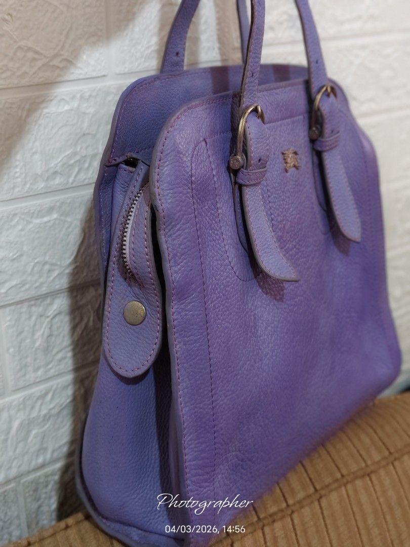 Burberry Purple Leather Handbag (Category: Luxury Bags & Wallets) located in Bulacan. Submitted by dstore4u (Listing ID 1430042203, Image 2). Description: Purple leather handbag with gold-tone hardware. Features a top handle design with buckle details. The interior has a check pattern lining. Includes a zipper closure with a Burberry branded zipper pull. The bag has a textured leather exterior and a small logo on the front. YKK Zipper isyu: With 