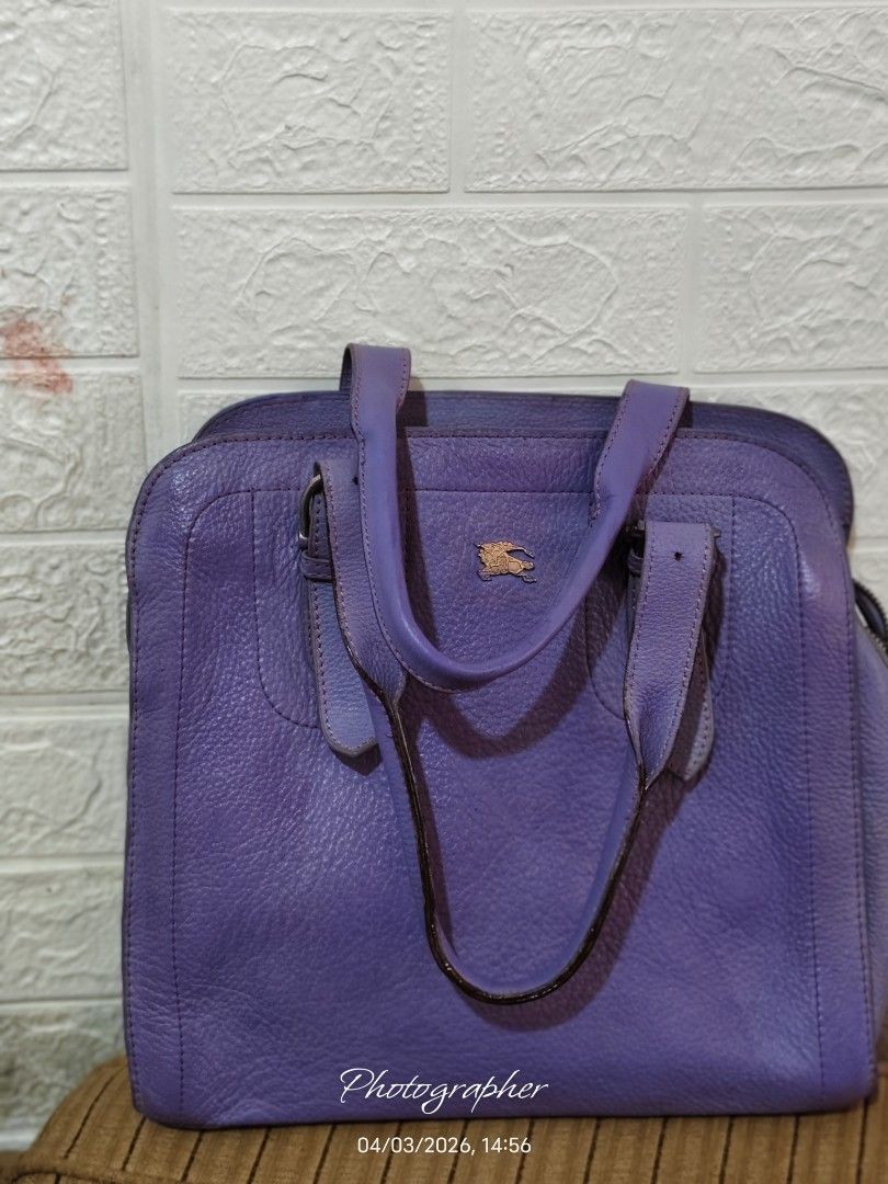 Burberry Purple Leather Handbag (Category: Luxury Bags & Wallets) located in Bulacan. Submitted by dstore4u (Listing ID 1430042203, Image 3). Description: Purple leather handbag with gold-tone hardware. Features a top handle design with buckle details. The interior has a check pattern lining. Includes a zipper closure with a Burberry branded zipper pull. The bag has a textured leather exterior and a small logo on the front. YKK Zipper isyu: With 