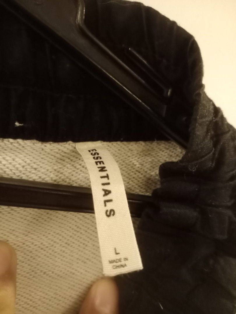 Fear of God Essentials Sweatpants (Category: Joggers) located in Manila. Submitted by thriftnmeal (Listing ID 1430183348, Image 3). Description: Gray sweatpants from Fear of God Essentials. Features a drawstring waist, black accents, and zippers at the ankles. The Essentials logo is visible on the tag. Made in China. Size L..