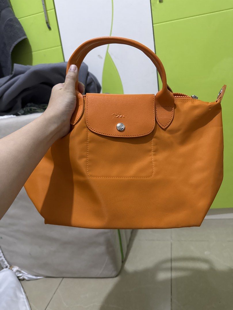 Longchamp Orange Handbag with Shoulder Strap (Category: Luxury Bags & Wallets) located in Malabon City. Submitted by jessibells (Listing ID 1430150214, Image 1). Description: Orange Longchamp handbag with a flap closure and a top handle. It features a zipper closure and includes a detachable shoulder strap. The interior has a pocket. The hardware is silver-toned..