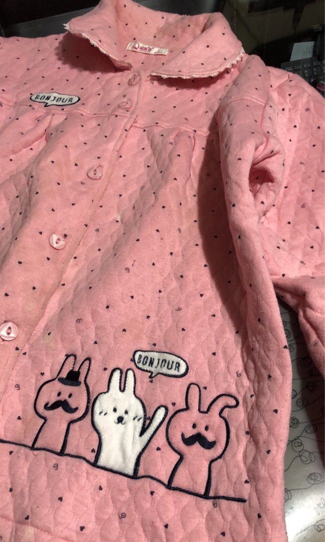 Pink Quilted Pajama Jacket with Cartoon Design (Category: Babies & Kids Fashion) located in Mandaluyong City. Submitted by jennyitems (Listing ID 1430210893, Image 2). Description: 👚 Pink pajama jacket features a quilted design with black polka dots. 🧥 It has a collar with lace trim, a button-up front, and two pockets. 🌸 The jacket is adorned with a "Bonjour" speech bubble and a cartoon bunny 🐰 🌸 The size tag indicates it is a size L. 🌸 So 