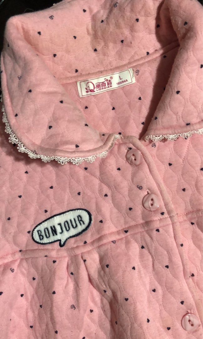 Pink Quilted Pajama Jacket with Cartoon Design (Category: Babies & Kids Fashion) located in Mandaluyong City. Submitted by jennyitems (Listing ID 1430210893, Image 3). Description: 👚 Pink pajama jacket features a quilted design with black polka dots. 🧥 It has a collar with lace trim, a button-up front, and two pockets. 🌸 The jacket is adorned with a "Bonjour" speech bubble and a cartoon bunny 🐰 🌸 The size tag indicates it is a size L. 🌸 So 