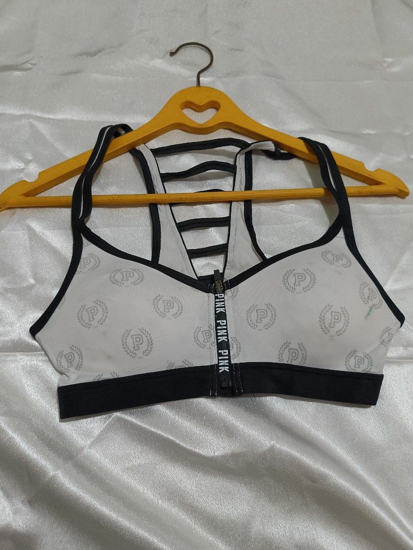 Pink Victoria's Secret Ultimate Sports Bra XS (Category: Activewear) located in Bago City. Submitted by cossacloset (Listing ID 1430053036, Image 1). Description: Pink Victoria's Secret Ultimate sports bra in size XS. Features a white base with the Pink logo pattern, black trim, and a zipper closure. The back has a strappy design with pink lining. The tag indic ates it is an Ultimate sports bra. The bra is designed for athletic activities. Prelov