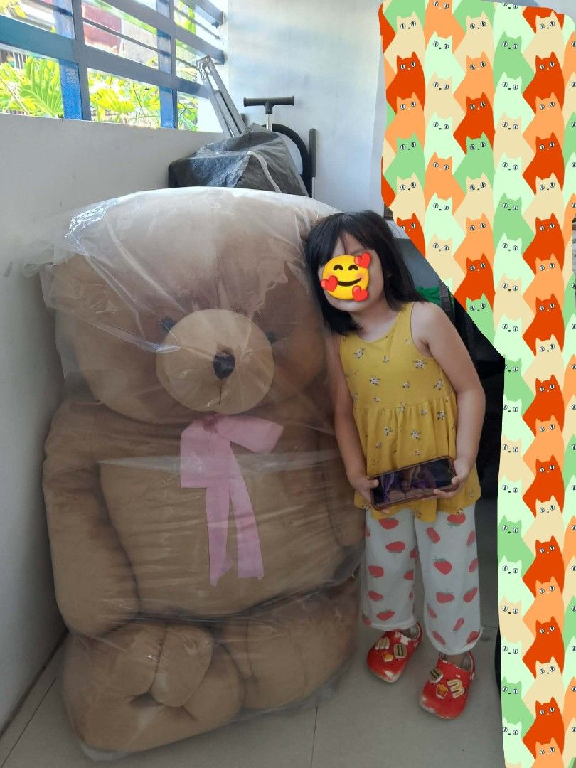Bear Cuddler Giant Teddy Bear (Category: Plushies & Soft Toys) located in Manila. Submitted by bodstyle (Listing ID 1430267275, Image 2). Description: Large Bear Cuddler teddy bear. It has a light brown fur, a pink ribbon, and a brown nose. The bear is very big, as shown in the images. It comes with a Bear Cuddler blanket. The original price tag is still attached, showing the price of ₱4,825.00. may lalagyan pa sya. good as new po ito walang issu