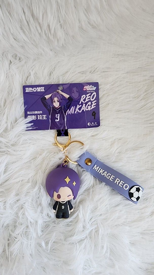 Blue Lock Mikage Reo Keychain (Category: Character Goods) located in Manila. Submitted by quickocean (Listing ID 1430273107, Image 1). Description: Keychain features Mikage Reo from the anime series. It includes a purple character charm, a strap with the name "Mikage Reo", and a soccer ball detail. Also included is a card featuring Mikage Reo..