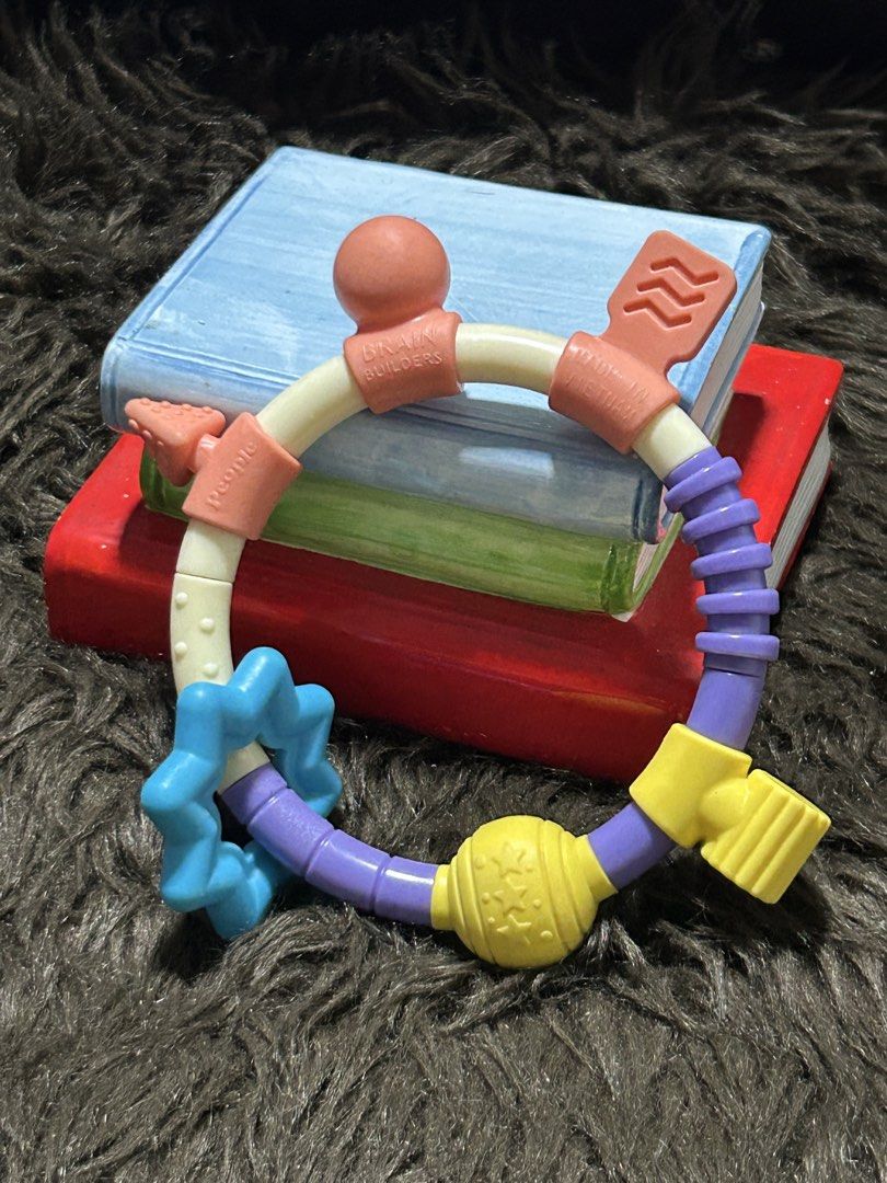 Bo25Brain Builders Teether (Category: Soothers & Pacifiers) located in Angeles City. Submitted by zyeplustradings (Listing ID 1430235228, Image 1). Description: Brain Builders teether features a colorful design with various textures and shapes. It includes a star-shaped element, a textured ball, and multiple sections for easy gripping. The teether is designed with different colors and textures to stimulate a baby's senses. It is made of safe mate