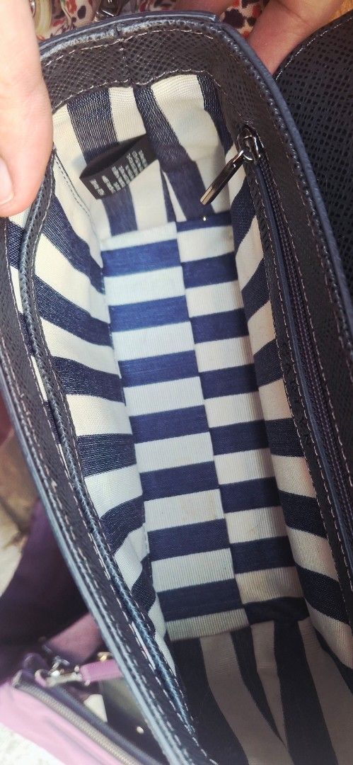 Carlyn Handbag with Silver Hardware (Category: Luxury Bags & Wallets) located in Manila. Submitted by bee.geema (Listing ID 1430270490, Image 2). Description: Carlyn handbag features a structured design with a silver clasp closure. The interior has a striped blue and white lining and a zippered pocket. The bag has a top handle and a detachable strap. The exterior is a textured dark blue material. The hardware is silver-toned, and the brand name i