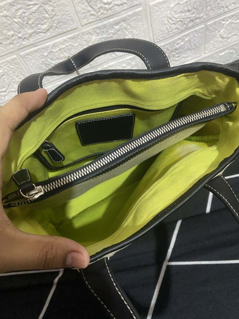 Coach Tote Bag with Black Leather Trim (Category: Luxury Bags & Wallets) located in Cavite. Submitted by calix0613 (Listing ID 1430254854, Image 2). Description: Coach tote bag features a cream-colored canvas body with black leather trim and handles. It has a zippered interior pocket and a bright yellow lining. The bag includes a Coach hang tag. The stitching is white, providing a nice contrast. The bottom of the bag is also black leather..