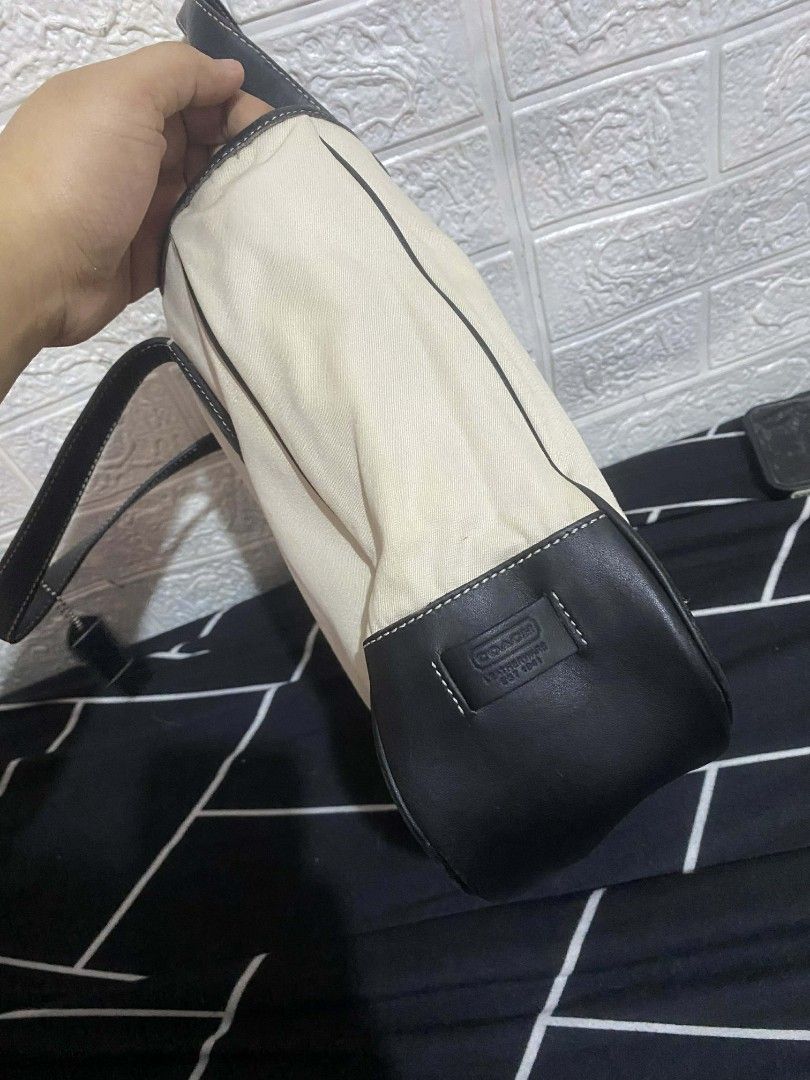 Coach Tote Bag with Black Leather Trim (Category: Luxury Bags & Wallets) located in Cavite. Submitted by calix0613 (Listing ID 1430254854, Image 3). Description: Coach tote bag features a cream-colored canvas body with black leather trim and handles. It has a zippered interior pocket and a bright yellow lining. The bag includes a Coach hang tag. The stitching is white, providing a nice contrast. The bottom of the bag is also black leather..