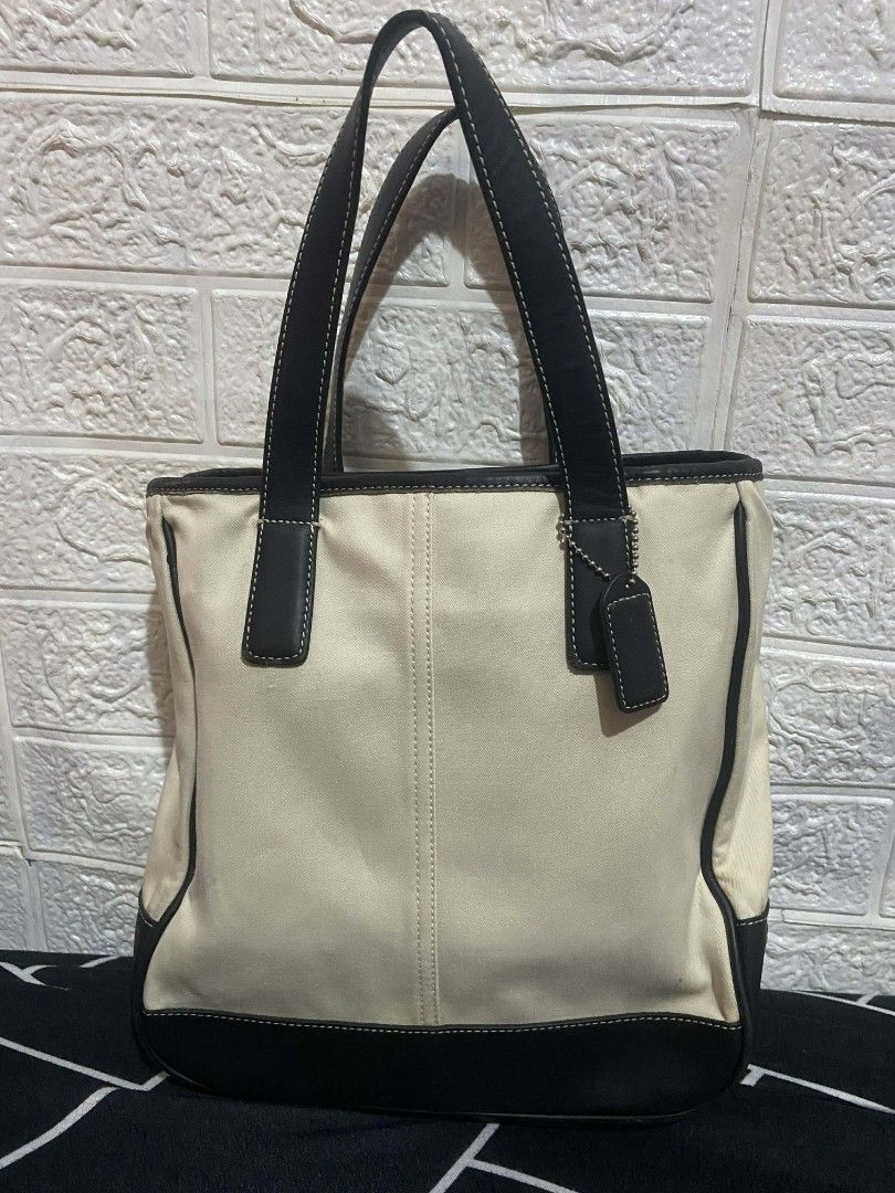 Coach Tote Bag with Black Leather Trim (Category: Luxury Bags & Wallets) located in Cavite. Submitted by calix0613 (Listing ID 1430254854, Image 1). Description: Coach tote bag features a cream-colored canvas body with black leather trim and handles. It has a zippered interior pocket and a bright yellow lining. The bag includes a Coach hang tag. The stitching is white, providing a nice contrast. The bottom of the bag is also black leather..