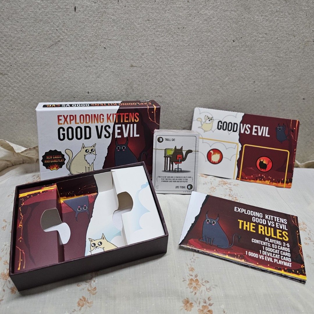 Exploding Kittens: Good vs Evil Card Game (Category: Board Games & Puzzles) located in Manila. Submitted by shopwithella.ph (Listing ID 1430304716, Image 3). Description: Exploding Kittens: Good vs Evil card game. Includes 93 cards, 1 rule book, and 1 Good vs Evil playmat. For 2-5 players. Features new cards and gameplay. Outsmart your opponent with brand new Armageddon cards. The last player left alive wins the game..