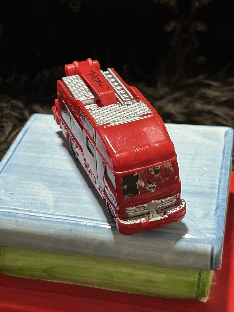 Fire Truck Toy (Category: Kids Toys) located in Angeles City. Submitted by zyeplustradings (Listing ID 1430235476, Image 1). Description: Red fire truck toy with a ladder and other details. Features Japanese text and markings. The toy has some wear and tear on the front..
