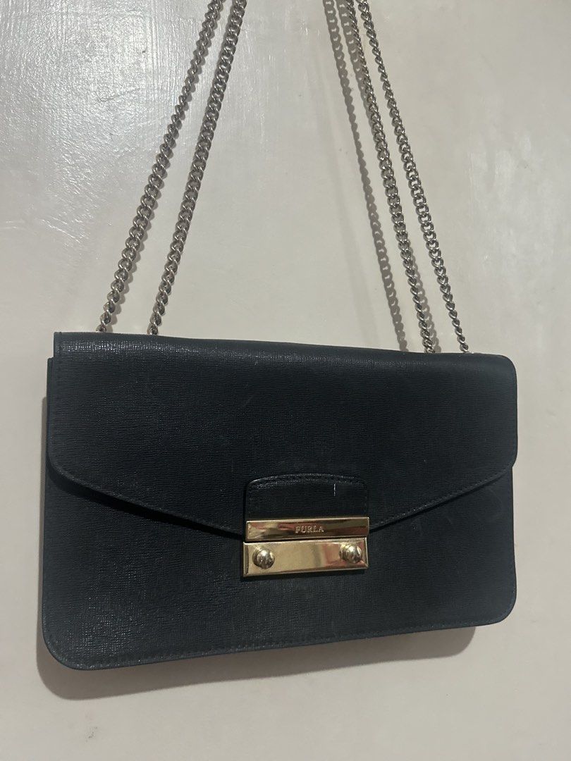 Furla Saffiano Leather Flap Bag (Category: Luxury Bags & Wallets) located in Tuguegarao City. Submitted by heartdeclutters (Listing ID 1430236307, Image 2). Description: Authentic! Black Furla shoulder bag with a chain strap. Features a gold-tone clasp closure with the Furla logo. It has a rectangular shape with a flap closure. The chain strap is silver-colored..