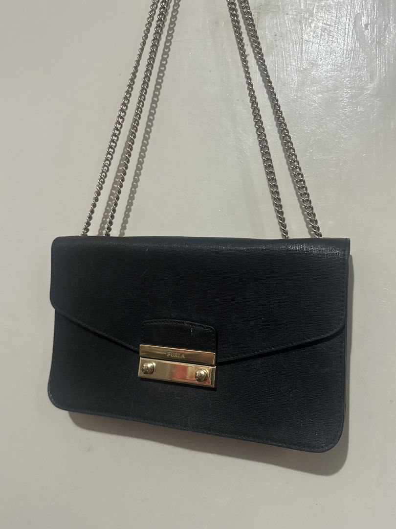 Furla Saffiano Leather Flap Bag (Category: Luxury Bags & Wallets) located in Tuguegarao City. Submitted by heartdeclutters (Listing ID 1430236307, Image 1). Description: Authentic! Black Furla shoulder bag with a chain strap. Features a gold-tone clasp closure with the Furla logo. It has a rectangular shape with a flap closure. The chain strap is silver-colored..