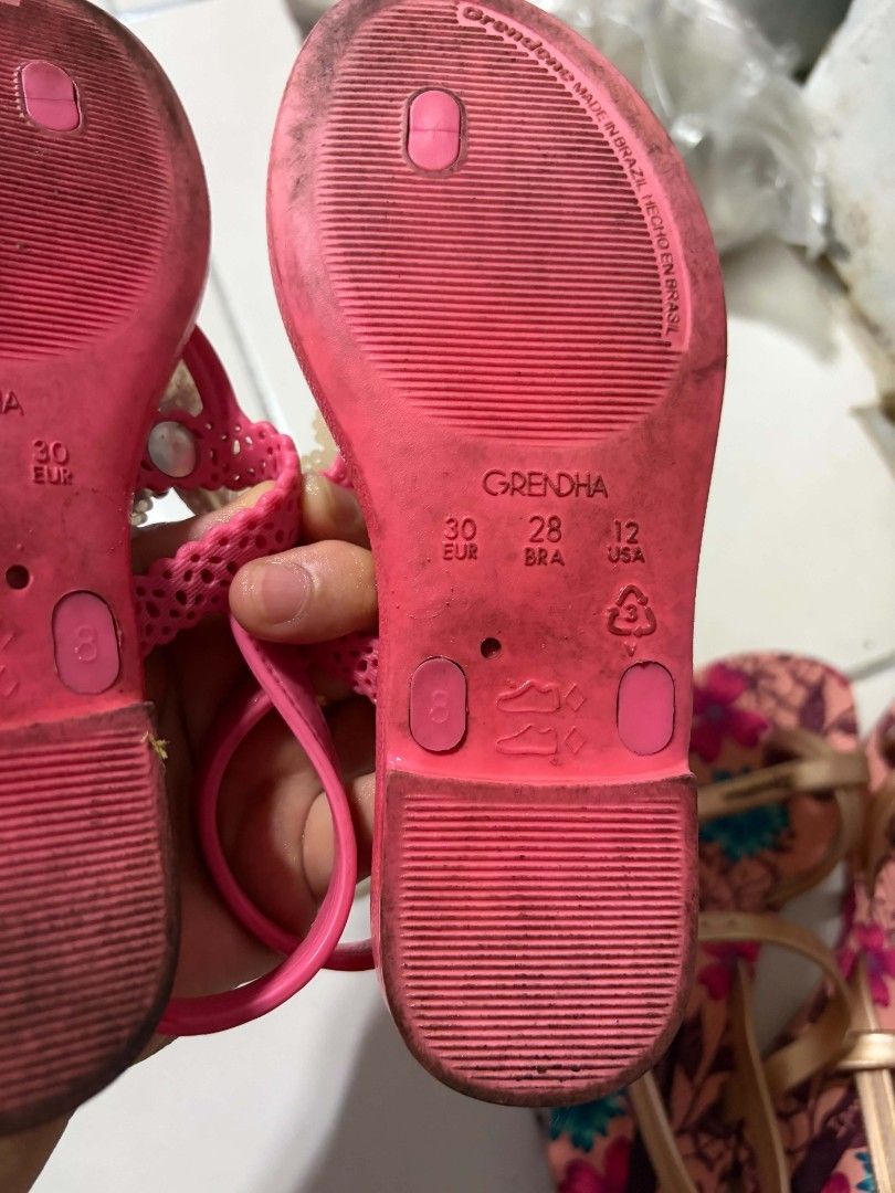 Grendha Butterfly Sandals Size 30 (Category: Babies & Kids Fashion) located in Valenzuela. Submitted by senia09 (Listing ID 1430222552, Image 2). Description: Pink Grendha sandals with butterfly accents. Features a checkered pattern on the footbed. Size 30, as indicated on the sole. The sandals have a thong style design with a strap that goes around the ankle. The sole is pink and shows some wear..