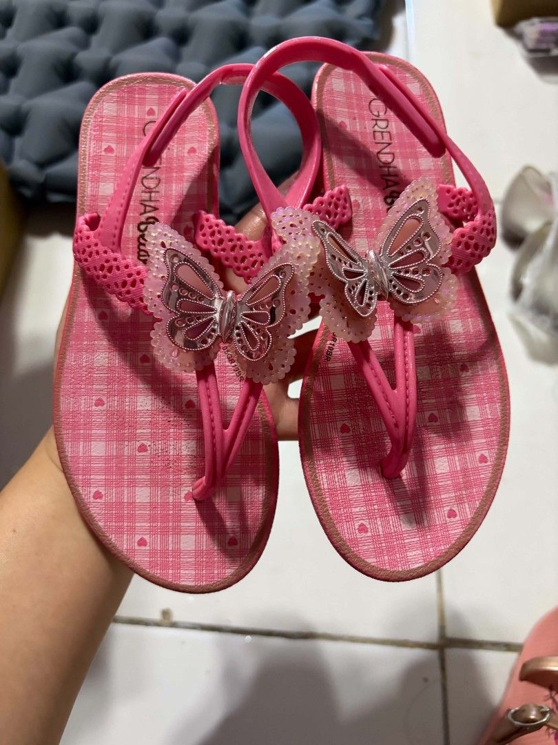 Grendha Butterfly Sandals Size 30 (Category: Babies & Kids Fashion) located in Valenzuela. Submitted by senia09 (Listing ID 1430222552, Image 1). Description: Pink Grendha sandals with butterfly accents. Features a checkered pattern on the footbed. Size 30, as indicated on the sole. The sandals have a thong style design with a strap that goes around the ankle. The sole is pink and shows some wear..