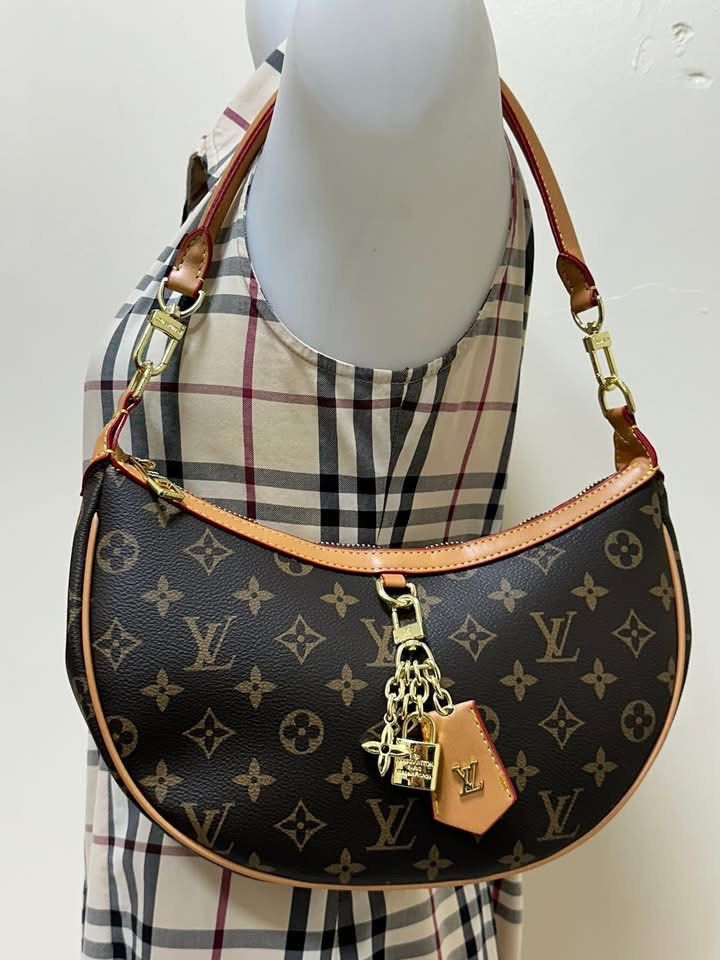 LV Croissant PM Handbag (Category: Luxury Bags & Wallets) located in Los Banos. Submitted by ditasbautista2329 (Listing ID 1430291979, Image 1). Description: Louis Vuitton Croissant PM handbag in brown monogram .Features a crescent shape with a red leather trim and a top zipper closure. Includes a gold-tone chain with a padlock charm and a leather tag. The interior is lined with a burgundy fabric and has a small pocket. Includes a serial number i