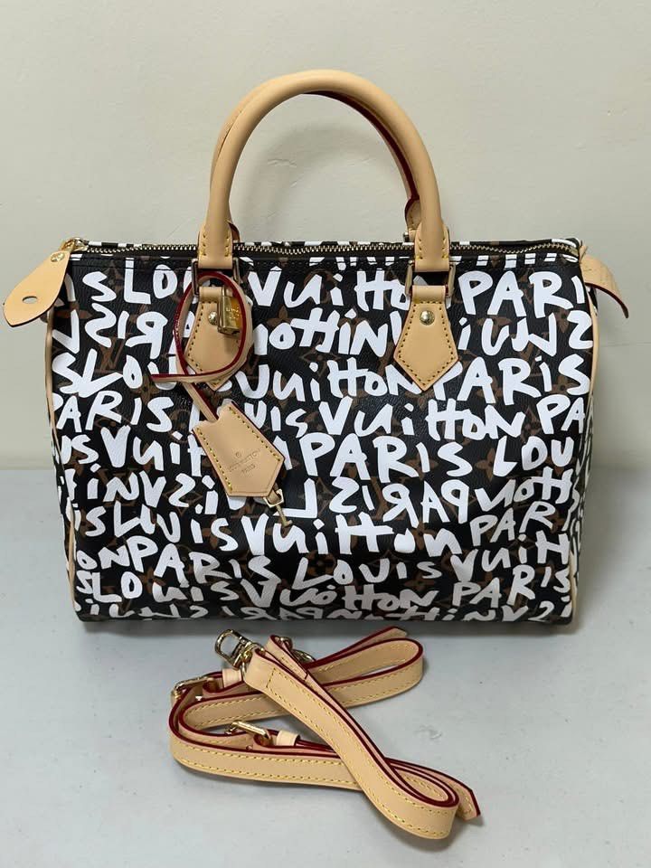 LV Graffiti Speedy 30 (Category: Luxury Bags & Wallets) located in Los Banos. Submitted by ditasbautista2329 (Listing ID 1430290685, Image 1). Description: Lv Speedy 30 handbag with graffiti print. Features a top zip closure, dual top handles, and an adjustable shoulder strap. The interior is lined with brown fabric. Includes a luggage tag. The hardware is gold-toned. The date code is SP0168..