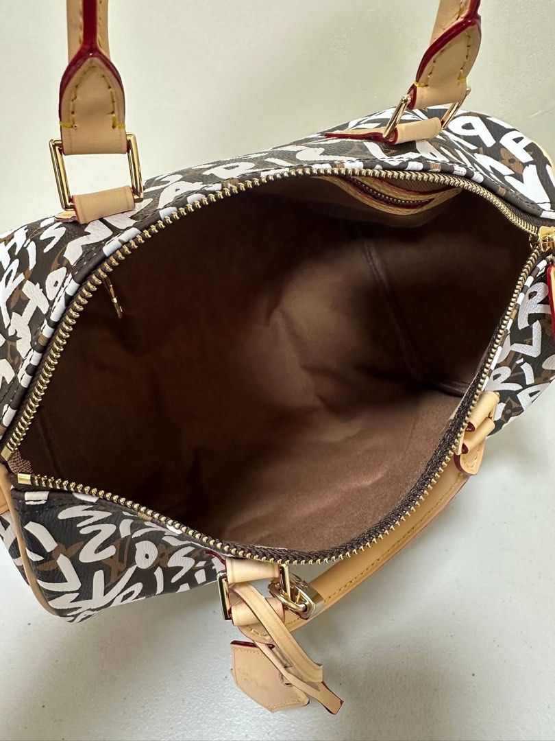 LV Graffiti Speedy 30 (Category: Luxury Bags & Wallets) located in Los Banos. Submitted by ditasbautista2329 (Listing ID 1430290685, Image 3). Description: Lv Speedy 30 handbag with graffiti print. Features a top zip closure, dual top handles, and an adjustable shoulder strap. The interior is lined with brown fabric. Includes a luggage tag. The hardware is gold-toned. The date code is SP0168..