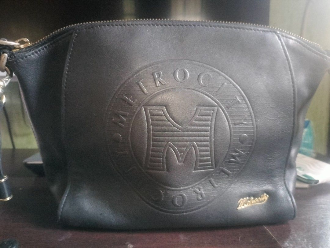 Metrocity Black Handbag sling (Category: Luxury Bags & Wallets) located in Cavite. Submitted by annasoriano1982 (Listing ID 1430316982, Image 1). Description: Black Metrocity handbag with a gold zipper and a detachable strap. Features the Metrocity logo embossed on the front. The interior includes a small pocket and a Metrocity label. Includes a detachable strap. The bag has a gold Metrocity logo on the front. only sign of use.