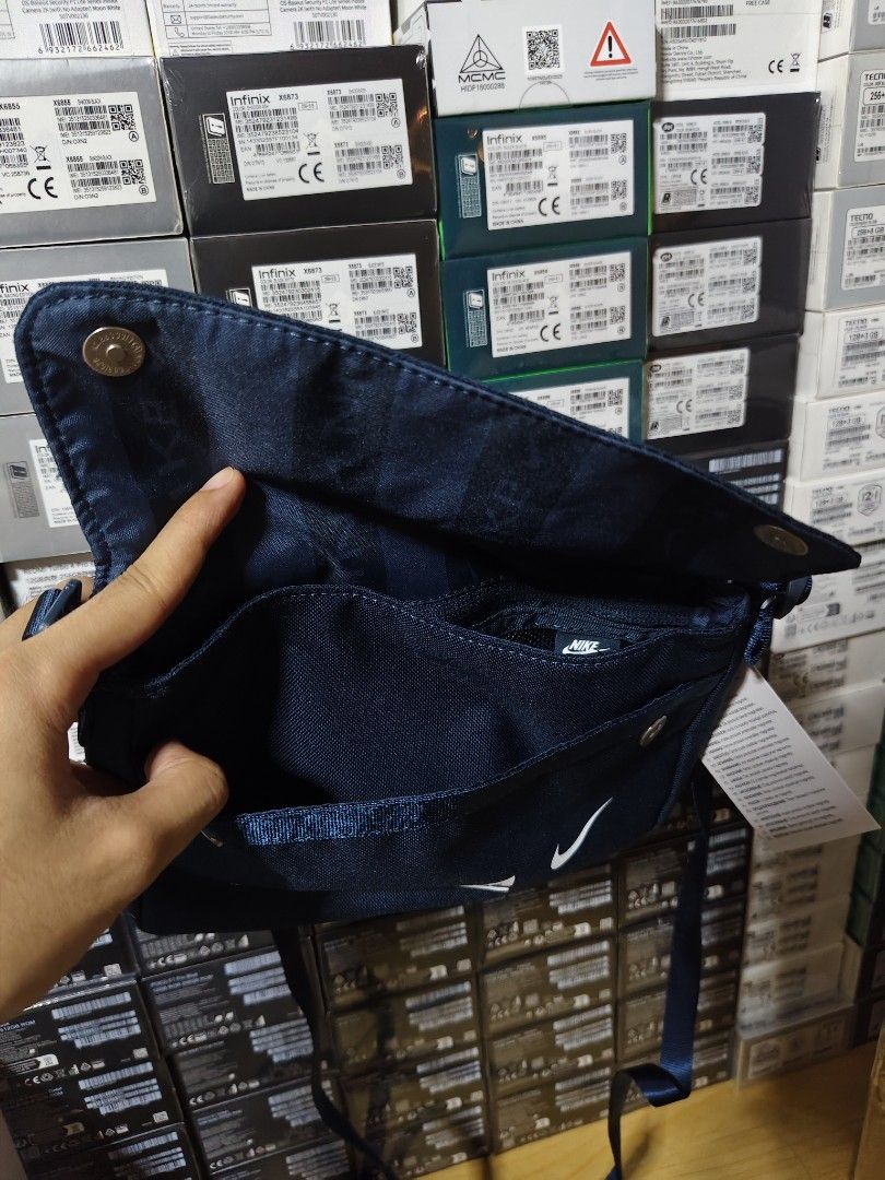 Nike Crossbody Bag (Category: Cross-body Bags) located in Marilao. Submitted by declutterwjosh13 (Listing ID 1430352037, Image 2). Description: Navy blue Nike crossbody bag. Features a main compartment with a zipper closure and multiple internal pockets. Includes an adjustable strap. The bag has the Nike logo printed on the front. Comes with tags attached..