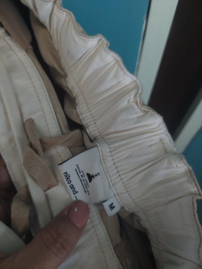 Niko and... Beige Pants - Size M (Category: Other Bottoms) located in Quezon City. Submitted by miyascloset (Listing ID 1430288267, Image 3). Description: Beige pants from Niko and. with a drawstring and button closure. Features a size M tag. The pants have a relaxed fit and appear to be made of a lightweight fabric. Details include stitching along the seams and a comfortable elastic waistband. for sale Niko and... hardly used drawstring khaki pa