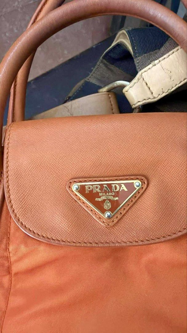 Original Prada Orange Nylon Handbag🧡 (Category: Luxury Bags & Wallets) located in Manila. Submitted by luxurycollectionhouse (Listing ID 1430269701, Image 3). Description: Authentic Prada handbag in a vibrant orange color. Features a top handle and a detachable shoulder strap. The interior is lined with orange fabric and includes a Prada Milano label. The bag has gold-tone hardware, including zippers and a Prada logo on the front flap. Made in I