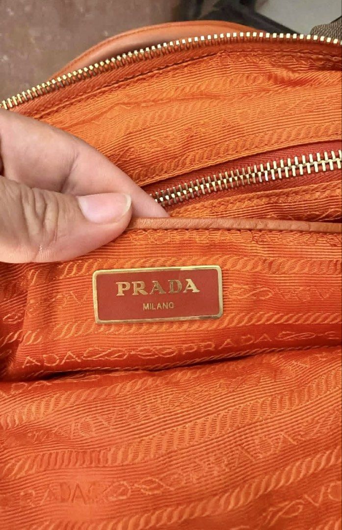 Original Prada Orange Nylon Handbag🧡 (Category: Luxury Bags & Wallets) located in Manila. Submitted by luxurycollectionhouse (Listing ID 1430269701, Image 2). Description: Authentic Prada handbag in a vibrant orange color. Features a top handle and a detachable shoulder strap. The interior is lined with orange fabric and includes a Prada Milano label. The bag has gold-tone hardware, including zippers and a Prada logo on the front flap. Made in I