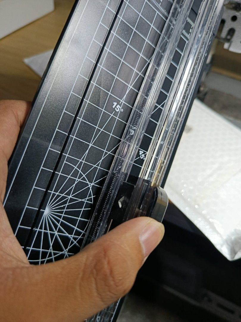 Paper Cutter (Category: Craft Supplies & Tools) located in Bacolod. Submitted by anikaniknianyel (Listing ID 1430317334, Image 3). Description: Paper cutter features a black cutting board with grid lines and angle markings. It has a clear plastic guide for precise cuts. The cutter has a sliding blade mechanism. The brand name is visible on the sliding blade. It is suitable for various paper sizes..