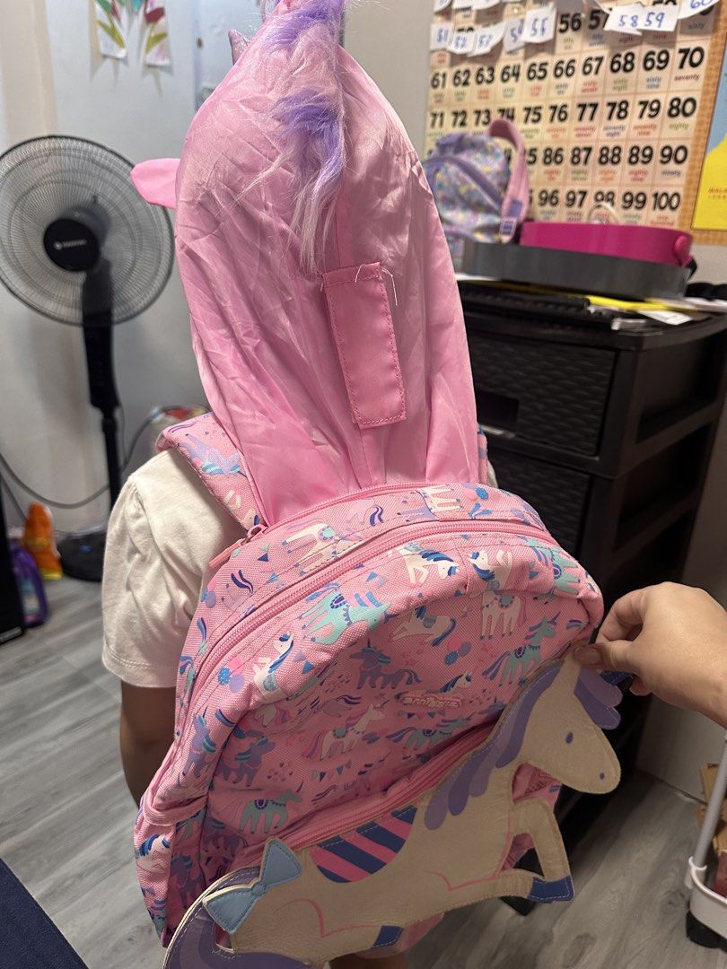 Smiggle Unicorn Backpack (Category: Babies & Kids Fashion) located in Valenzuela. Submitted by mommyiish (Listing ID 1430268214, Image 1). Description: - Smiggle Unicorn Backpack - Fun unicorn design - Pink exterior with unicorn graphics - Large unicorn-shaped pocket - Includes matching unicorn hood - Pink interior with Smiggle logo - Adjustable straps - Top handle.