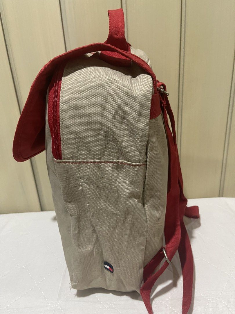 Tommy Hilfiger Red and Beige Backpack (Category: Luxury Bags & Wallets) located in Mandaluyong City. Submitted by kately18 (Listing ID 1430339676, Image 3). Description: Stylish Tommy Hilfiger backpack in red and beige. Features a top handle, adjustable straps, and a front flap closure with a metal ring detail. Includes a zippered front pocket and a heart-shaped charm. The interior has a Tommy Hilfiger tag. Perfect for everyday use..