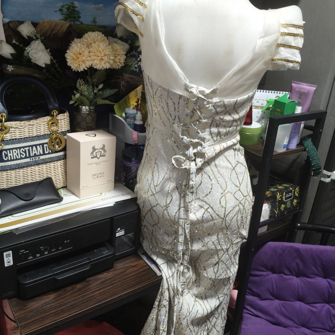 Elegant White Evening Dress (Category: Evening dresses & gowns) located in Manila. Submitted by stuff_finder (Listing ID 1430507307, Image 2). Description: Stunning white evening dress with intricate gold detailing. Features a flattering V-neckline and a high slit. The back has a corset-style closure for a customizable fit. The dress has delicate cap sleeves with gold accents. Perfect for special occasions..