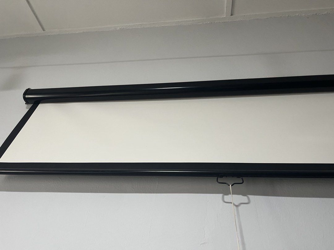 Manual Pull Down Projector Screen (Category: Projectors) located in Kuala Lumpur. Submitted by jemin (Listing ID 1430438491, Image 2). Description: Manual pull-down projector screen. It is black and white in color. The screen is mounted on the wall. It has a pull-down cord for easy operation. Width: 200cm.