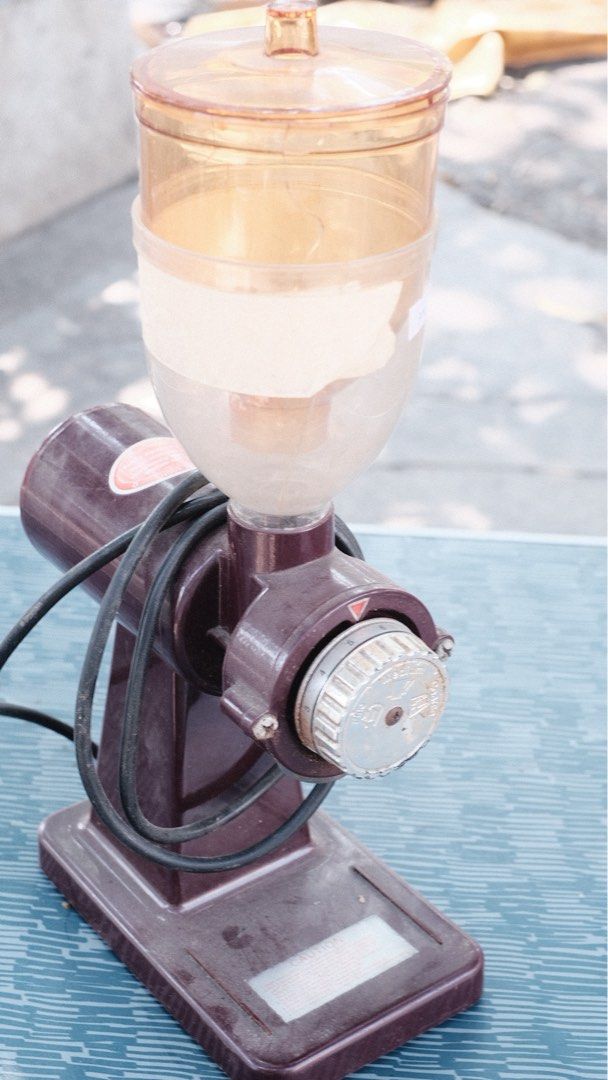 Vintage Coffee Grinder (Category: Coffee Machines & Makers) located in Las Pinas. Submitted by yourchaiboy (Listing ID 1430434152, Image 1). Description: Vintage coffee grinder features a clear hopper and a dark maroon body. It has a dial for adjusting the grind size. The grinder has a power cord and a rectangular base..