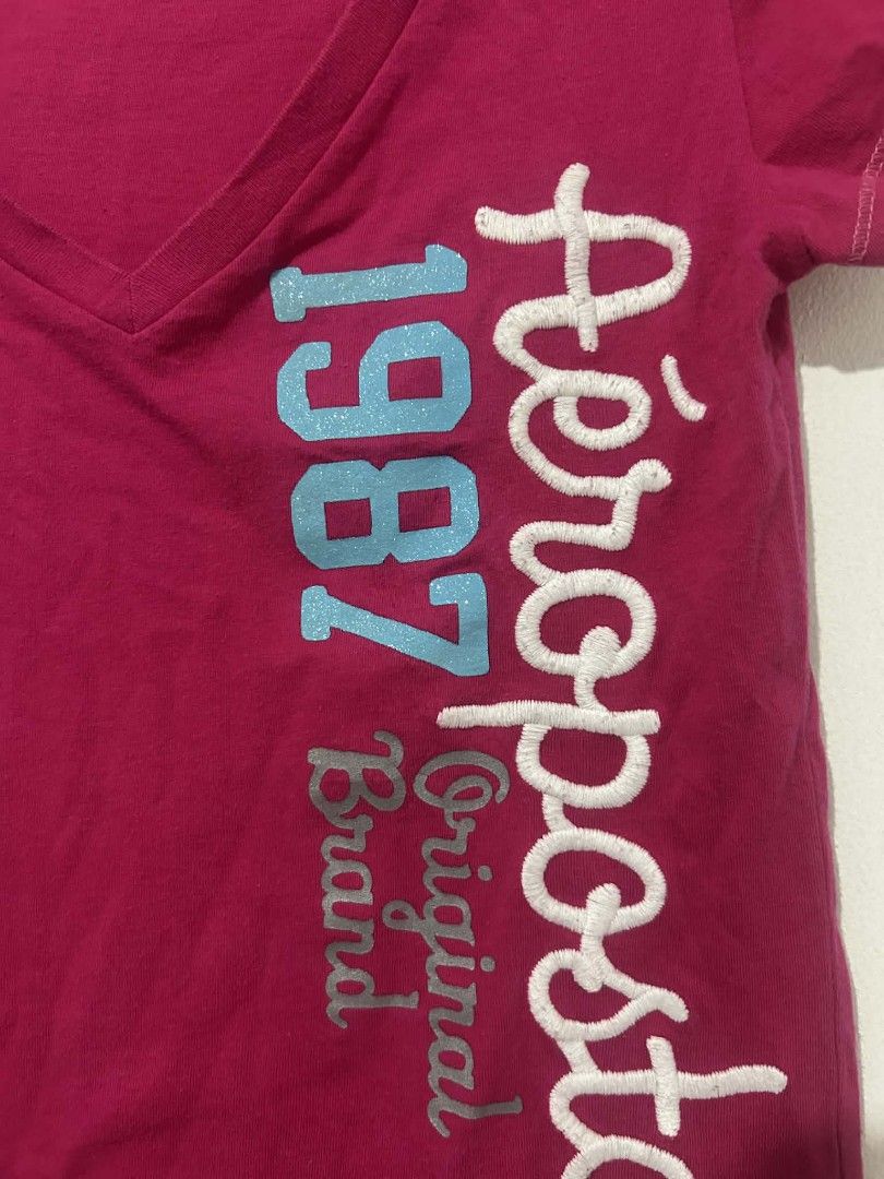 Aéropostale V-neck T-shirt (Category: Shirts) located in Naga. Submitted by shiyaaah (Listing ID 1430781374, Image 3). Description: BODY HUGGING! Aéropostale V-neck T-shirt in pink. Features the brand name and "1987 Original Brand" printed on the front. The shirt has short sleeves and a V-neck design. The size is M/M. Tags: y2k, whimsy, whimsical, hollister, abercrombie, body hugging.