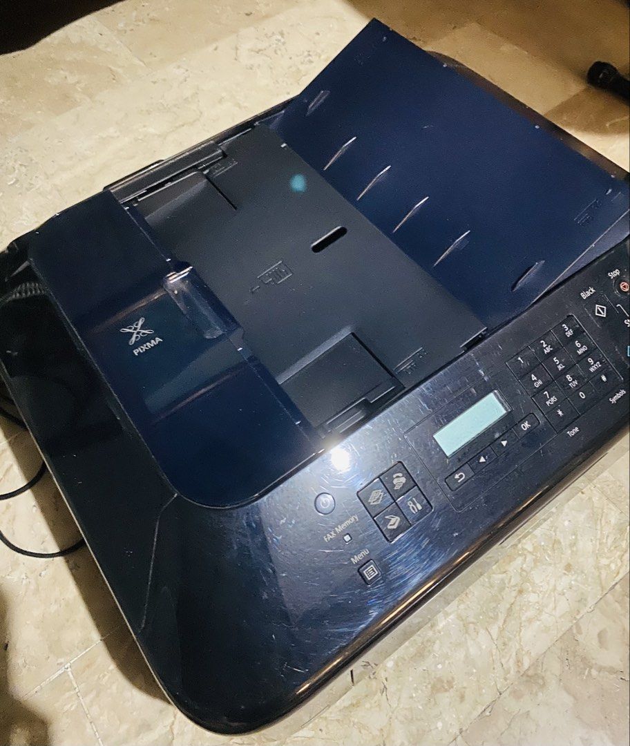 Canon PIXMA Printer (Category: Printers, Scanners & Copiers) located in Manila. Submitted by maloudear (Listing ID 1430616928, Image 3). Description: Canon PIXMA printer with scanner and copier functions. Features a control panel with buttons and a digital display. Includes a power cord. The printer has a black finish and a top-loading paper tray. The scanner lid opens fully. The Canon logo is visible on the front..